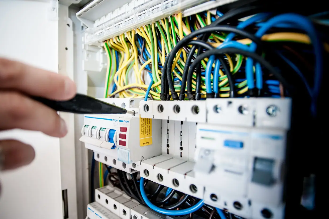 Illustrative photo of an open switchboard with a hand at the breakers. Not Brite Sparx staff or a Brite Sparx job.
